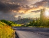 stock-photo-asphalt-road-going-to-high-mountains-down-the-hill-and-passes-through-the-green-shad