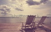 stock-photo-white-wooden-beach-chair-facing-seascape-vintage-filter-effect-186962285